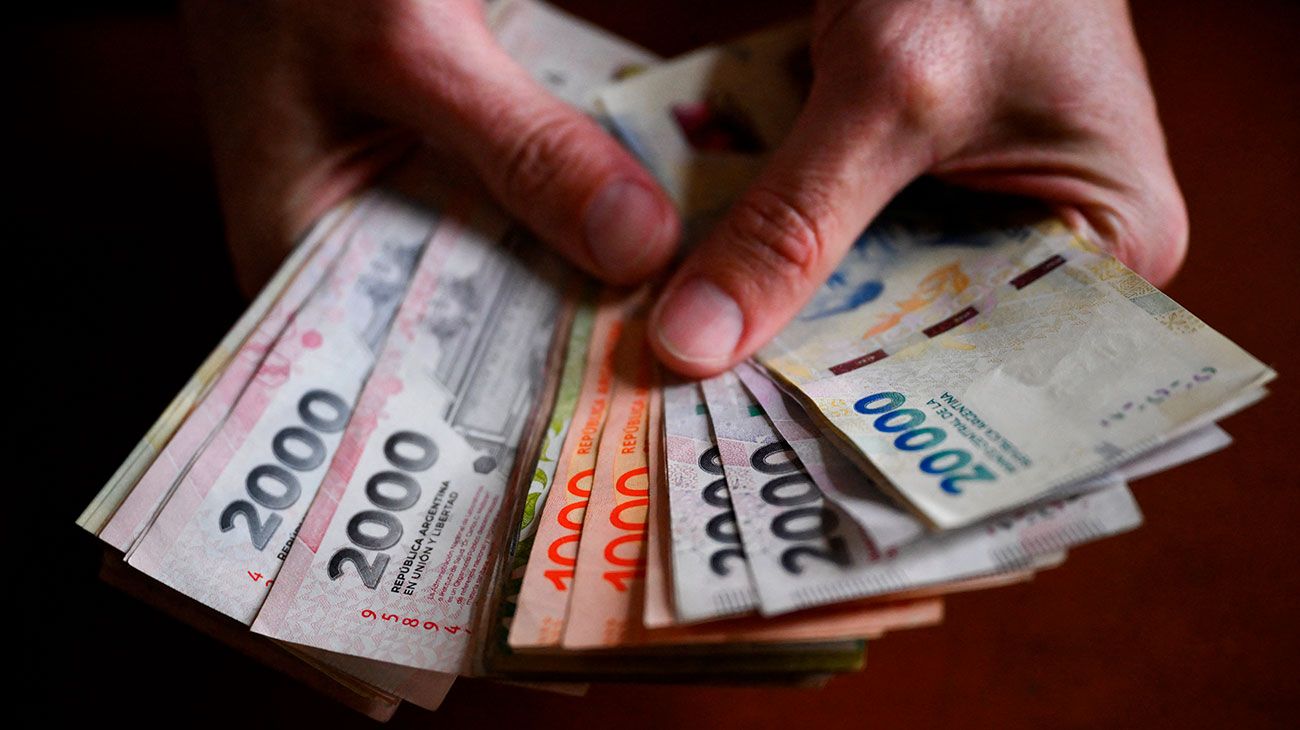 Manos contando billetes de pesos argentinos
